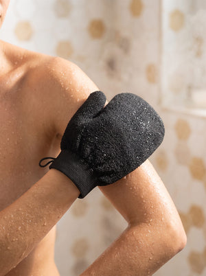 Exfoliating mitt being used on a wet arm in the shower
