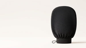 Black exfoliating mitt standing upright, showing its woven viscose texture
